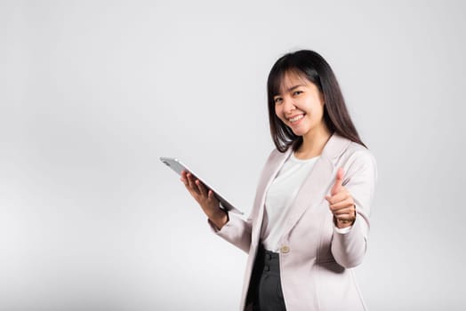 Portrait of Asian beautiful young woman smiling using tablet computer, Happy lifestyle female teen hold digital tablet pc and show thumb up for good sign, studio shot isolated on white background