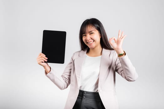 Asian beautiful young woman smiling using tablet computer, Happy female show blank screen digital tablet pc and show OK sing to accept, studio shot isolated on white background