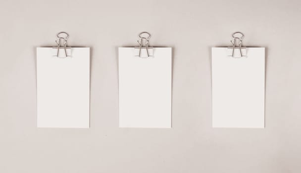 Blank white papers with a paperclip on a gray colored background, copy space for text, reminder or message in the office, communication concept