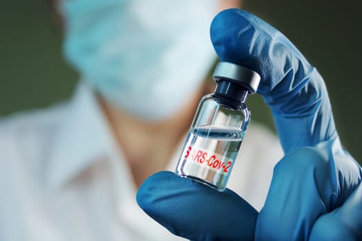 A female doctor holds a vial of vaccine in her hand. Hand close up..