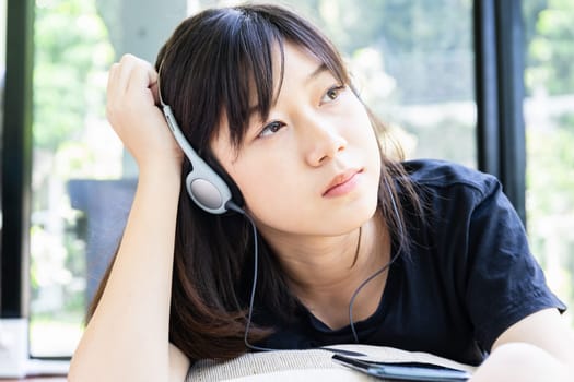 Teenage girl with headphones and listening to music from mobile phone at home