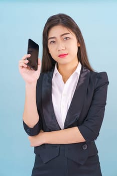 Young women in suit holding her phone standing against blue background