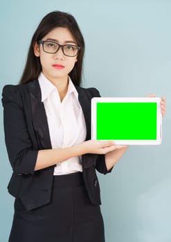 Young asian women in suit holding her digital tablet mock up standing against green background