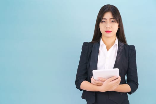 Young women standing in suit holding her digital tablet computor against blue background