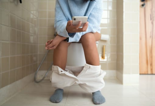 woman using phone while using the bathroom