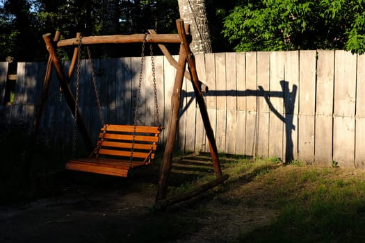 Swing wooden bench in a garden during a sunny day