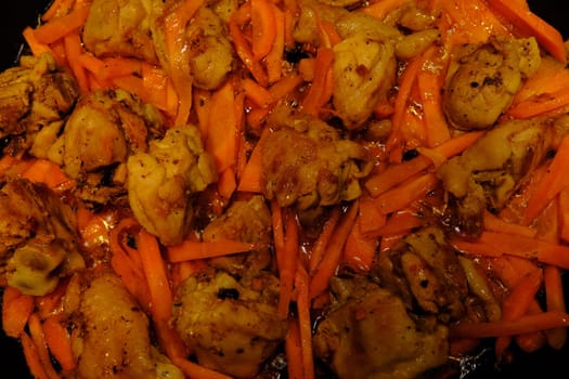 Homemade Korean Spicy chiken dish, frying chiken with carrot in a pan with sunflower oil