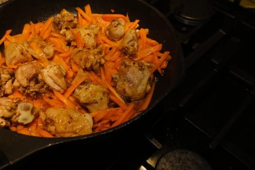 Homemade Korean Spicy chiken dish, frying chiken with carrot in a pan with sunflower oil