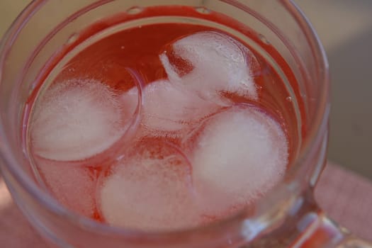 Glass of Roselle juice with ice. Traditional beverage. Herbal drink. Top view on wooden table