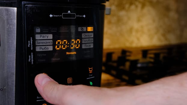 man using modern multi cooker in kitchen. choosing program.