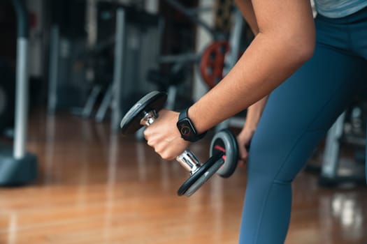 athlete woman lifting dumbbell, doing exercise at gym