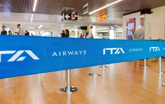 Rome, ITA, July 2022: blue belt barrier with white ITA Airways airlines logo. ITA Airways is the Italian flag carrier. Travel and airport security