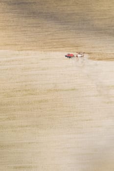 Aerial View. Tractor With Seed Drill Machine Sowing The Seeds For Crops In Spring Season. Beginning Of Agricultural Spring Season. Countryside Field Landscape. Natural Rural Background.