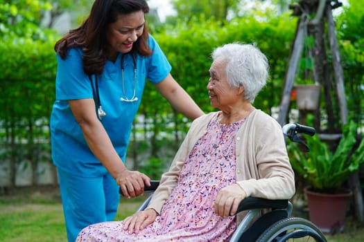 Doctor help Asian elderly woman disability patient sitting on wheelchair in park, medical concept.