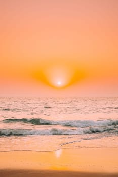 Sunset Sun Shine Above Sea. Natural Sunrise Sky Warm Colors Over Ripple Sea. Ocean Water Foam Splashes Washing Sandy Beach.