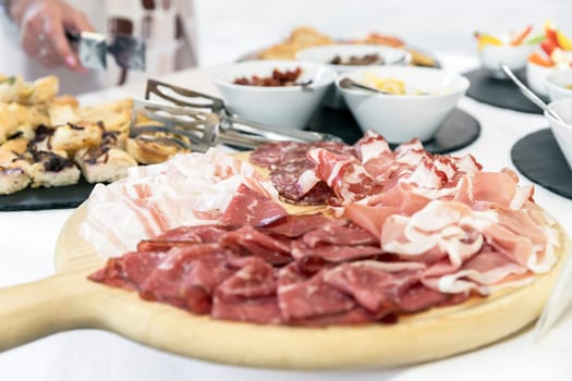 Wood cutting board with prosciutto, bacon, salami and bresaola. Meat platter.