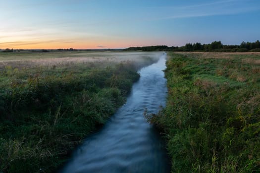 Small river and meadows with fog, view after sunset, Czulczyce, Poland