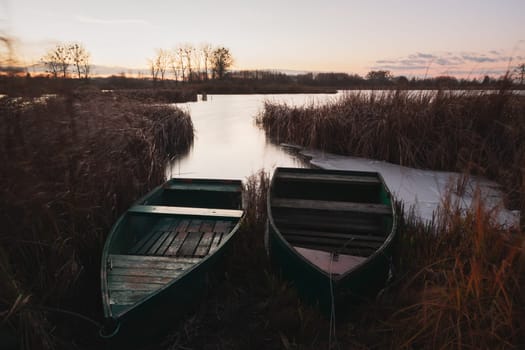 Fishing boats moored in the reeds of the lake, autumn evening