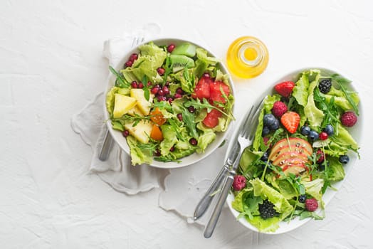 Fresh salad with fruits and greens on white background top view with space for text. Healthy food.