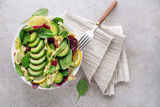 Healthy mixed salad with avocado on grey table background