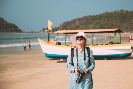 Canacona, Goa, India. Young Caucasian Lady Woman With Camera Standing On Famous Palolem Beach Near Arabian Sea In Summer Sunny Day.