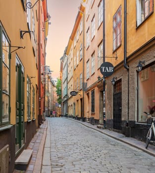 Stockholm, Sweden - June 26 2022: Narrow alley located in Gamla stan, the old town of Stockholm, Sweden with old style colorful houses and cobblestone street
