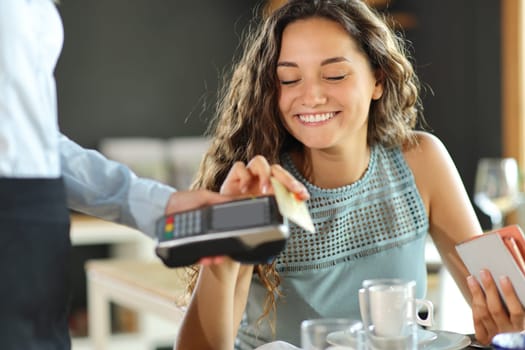 Happy woman paying lunch in a restaurant with credit card