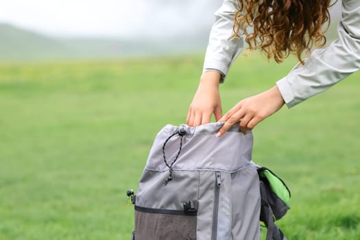 Close up portrait of a hiker searching inside of a backpack in the mountain