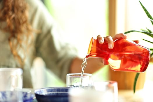 Close up portrait of a woman hand pouring water into a glass in a restaurant