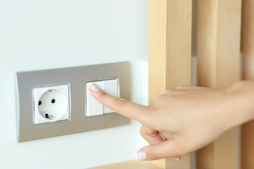 Close up of a woman hand pressing light switch in a room