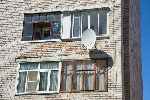 A satellite dish is hanging on the wall of a brick house. High quality photo