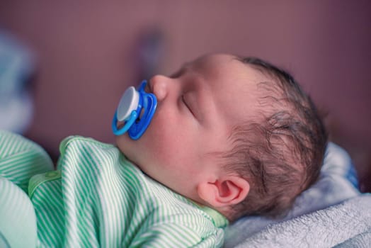 Face profile portrait of a sleeping newborn baby with a pacifier in his mouth