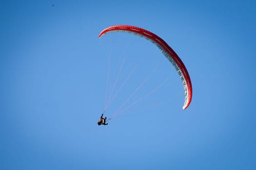 Paraglider, airborne in a clear blue sky