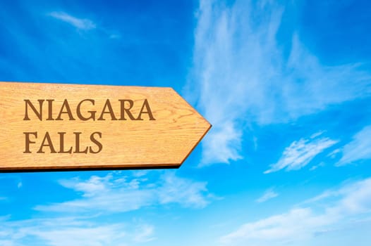Wooden arrow sign pointing destination NIAGARA FALLS against clear blue sky with copy space available. Travel destination conceptual image
