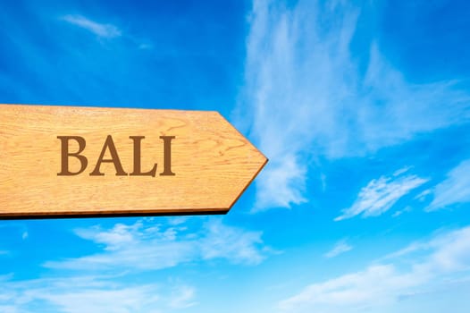 Wooden arrow sign pointing destination BALI against clear blue sky with copy space available. Travel destination conceptual image