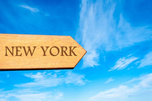 Wooden arrow sign pointing destination NEW YORK against clear blue sky with copy space available. Travel destination conceptual image