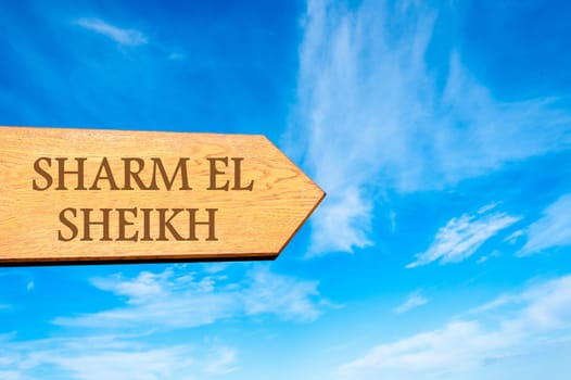 Wooden arrow sign pointing destination SHARM EL SHEIKH against clear blue sky with copy space available. Travel destination conceptual image