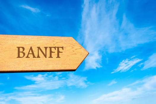 Wooden arrow sign pointing destination BANFF against clear blue sky with copy space available. Travel destination conceptual image