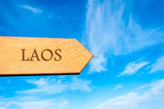 Wooden arrow sign pointing destination LAOS against clear blue sky with copy space available. Travel destination conceptual image