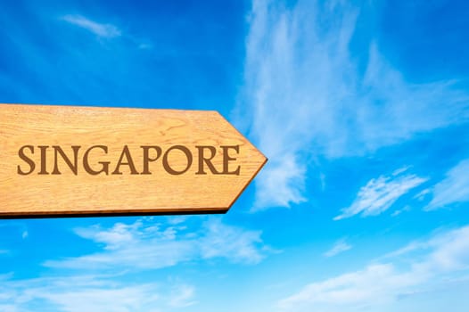Wooden arrow sign pointing destination SINGAPORE against clear blue sky with copy space available. Travel destination conceptual image