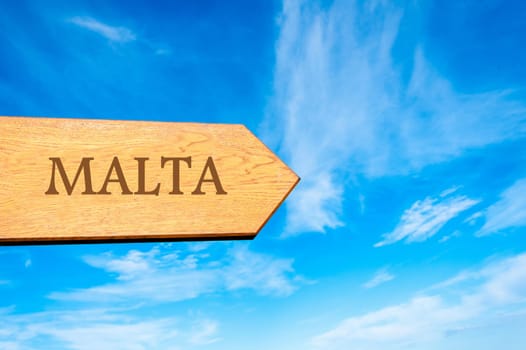 Wooden arrow sign pointing destination MALTA against clear blue sky with copy space available. Travel destination conceptual image