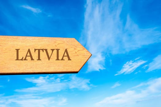 Wooden arrow sign pointing destination LATVIA against clear blue sky with copy space available. Travel destination conceptual image