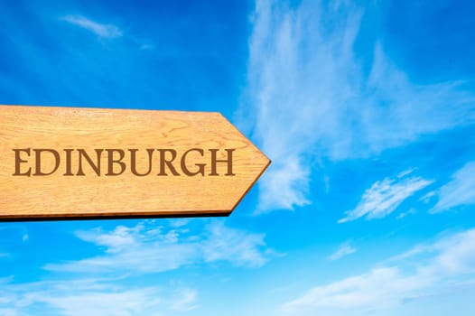 Wooden arrow sign pointing destination EDINBURGH, SCOTLAND against clear blue sky with copy space available. Travel destination conceptual image