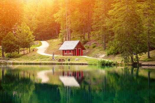 Lake fusine during a beautiful sunset with a small hut reflected in the water