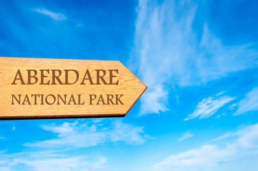 Wooden arrow sign pointing destination ABERDARE NATIONAL PARK against clear blue sky with copy space available. Travel destination conceptual image
