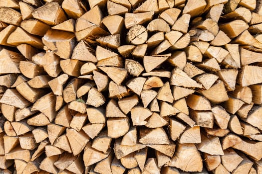 Background of chopped firewood stacked up on top of each other in a pile