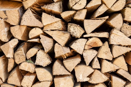 Background of chopped firewood stacked up on top of each other in a pile