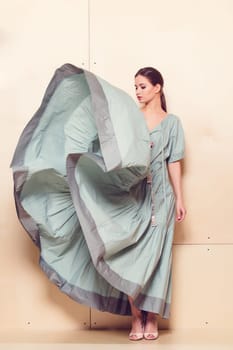 Full-length portrait of a lovely woman in romantic dress on wodden background