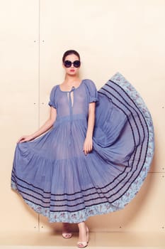 Full body slim woman in blue sundress on wooden background