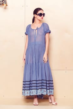 Full body slim woman in blue sundress on wooden background